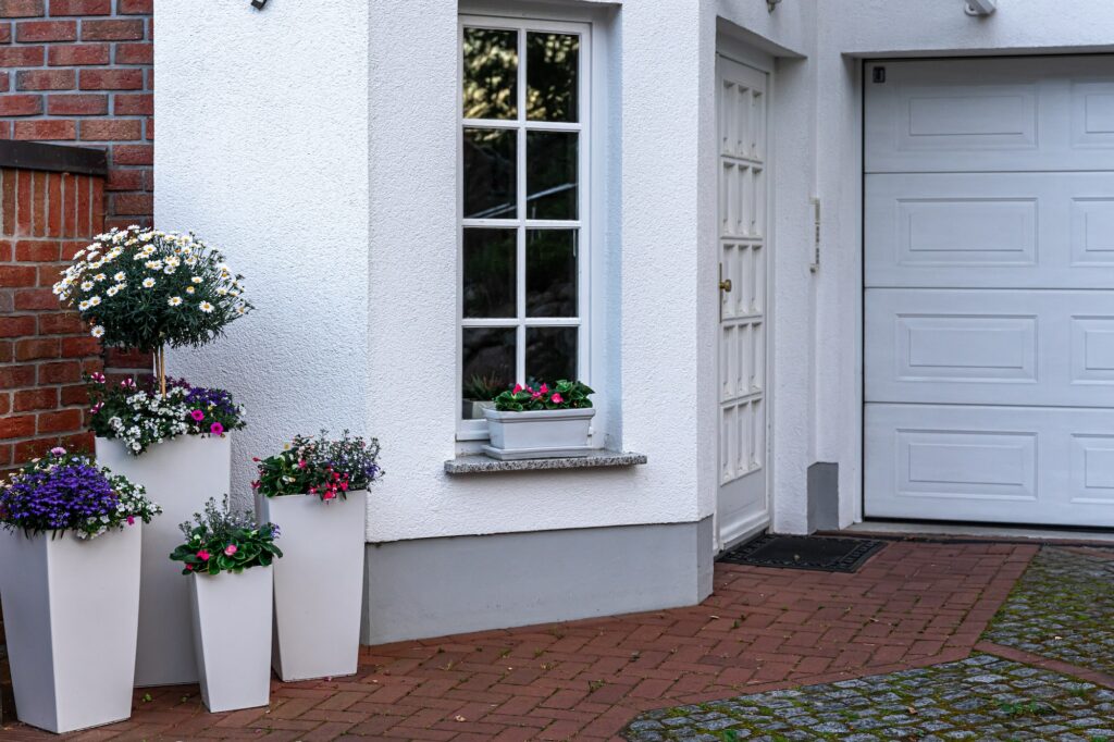 Part of the exterior of the house with white color with flowers.